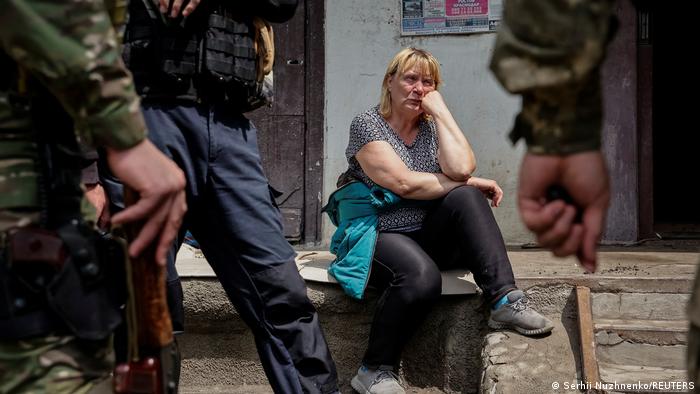 Мешканка Лисичанська сидить поряд зі своєю квартирою в оточенні працівників української поліції.  Фото 2 червня 2022 року 