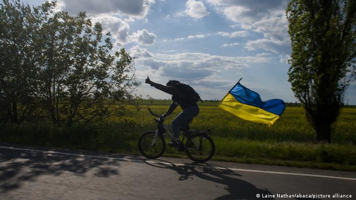 Велосипедист їде дорогою в регіоні між Миколаївом та Херсоном з прапором України, 15 травня 2022 року