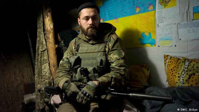 Чоловік Каті - 29-річний Максим - сидить на своєму ліжку у підземному бункері на лінії фронту на околицях Маріуполя.