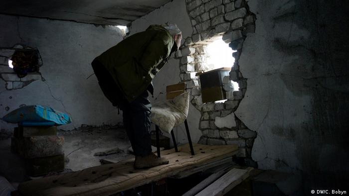 Солдат української армії спостерігає за позиціями сепаратистів через пробиту снарядом дірку у стіні колишнього санаторію на околицях Маріуполя.
