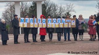 Учасники мітингу у Мелітополі тримають плакат із написом Мелітополь - це наша земля, березень 2022 року