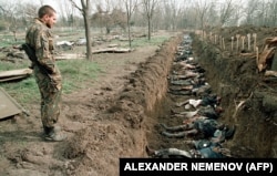 Солдат русской армии на Грозном кладбище смотрит на тела чеченских мирных жителей, убитых во время зимних боев и эксгумированных для идентификации, 31 марта 1995 года.