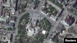 Супутниковий знімок зруйнованої будівлі театру в Маріуполі, поряд з яким з'явилися будівельні крани та вантажні машини, Україна, 12 травня 2022 року (фото надане Maxar Technologies)