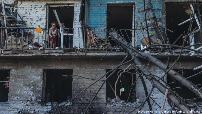 Жінка виглядає з дверного отвору в зруйнованій цегляній будівлі у Бахмуті.