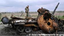 TOPSHOT - Український сервісний бік на забитому російським tank на руді в village Rusaniv, в Kyiv регіону на 16 квітня 2022 року. United Nations said on April 16, 2022, як інше 40,000 fled the country in 24 hours.  (Photo by Genya SAVILOV/AFP) (Photo by GENYA SAVILOV/AFP via Getty Images)