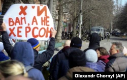 Люди стоят перед российскими войсками на улице во время митинга против оккупации в Херсоне, 14 марта 2022 года
