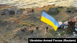 Украинские бойцы устанавливают национальный флаг на острове Змеиный в Черном море (Одесская область).  Фото опубликовано 7 июля 2022 года.  Ранее, после длительных интенсивных ударов ВСУ, российские военные, понеся большие потери, покинули остров