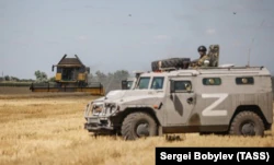 Военная машина России на украинском поле во время уборки урожая в ныне оккупированной части Херсонской области, фото от 21 июля
