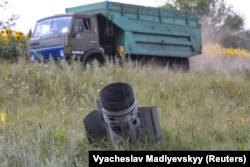 Грузовик с пшеницей проезжает мимо хвостовой части упавшей ракеты, застрявшей в поле в Харьковской области, фото от 30 июля