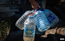 Житель Авдеевки пришел набрать воду в большие пластиковые бутылки (архивное фото)