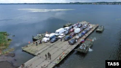 Автомобили на понтонном пароме, организованном российскими оккупантами возле поврежденного ударами ВСУ Антоновского моста через реку Днепр, 3 августа 2022 года