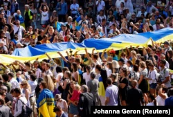 Люди несут гигантский украинский флаг в День Независимости Украины.  Брюссель, Бельгия, 24 августа 2022 года