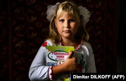 9-летняя Антонина с учебником украинского языка после онлайн-урока в первый учебный день у себя дома в селе Покровское Николаевской области неподалеку от фронта, 1 сентября 2022 года
