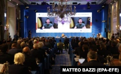 Президент Украины Владимир Зеленский (на экране) во время выступления через видеосвязь на церемонии открытия форума 
