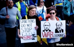 На одном из плакатов изображение президента России Владимира Путина и Александра Лукашенко с надписью «Военные преступники» на акции протеста против российского вторжения в Украину.  Лондон, 26 марта 2022 года