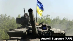 Украинские военнослужащие едут на танке по дороге в Луганскую область 21 июня 2022 года